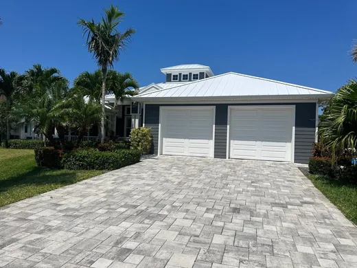 A finished white metal roof by Roofs Only Florida on a home with a paver driveway