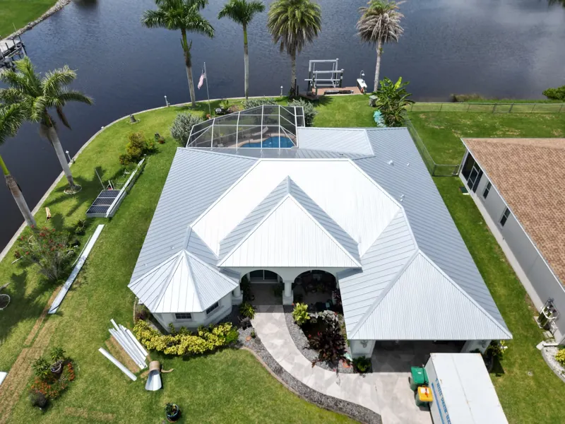 Mill-finish metal roof on a canal home with a pool