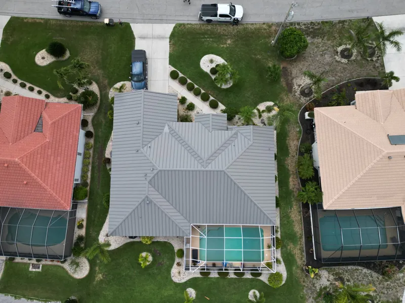Top-down view of a gray metal roof beside a pool cage